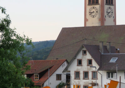 Juni 2019: Blick vom Schulweg zur Pfarrkirche St. Johannes. Die Straße ist mit Fahnen für das Fronleichnamsfest gesäumt.