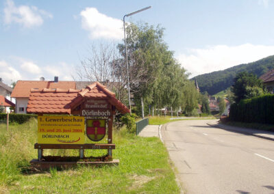 Juni 2004: Am Ortseingang wird auf die erste Gewerbeschau Dörlinbachs hingewiesen. Die Begrüßungstafel auf der Südseite stand damals noch auf der linken Seite.