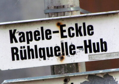 Der kuriose Wegweiser mit den Rechtschreibfehlern. Statt „Kapelle“ heißt es auf dem Schild „Kapele“ und statt „Ruhlquelle“ heißt es „Rühlquelle“.