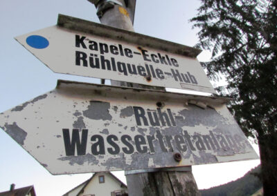 Der kuriose Wegweiser mit den Rechtschreibfehlern. Statt „Kapelle“ heißt es auf dem Schild „Kapele“ und statt „Ruhlquelle“ heißt es „Rühlquelle“.