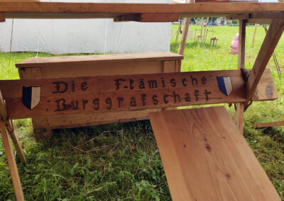 Der Gruppenname der Flämischen Burggrafschaft ist sowohl in Deutsch als auch in Flämisch an den Tischbeinen verewigt.