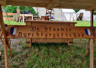 Der Gruppenname der Flämischen Burggrafschaft ist sowohl in Deutsch als auch in Flämisch an den Tischbeinen verewigt.