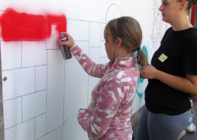 Momentaufnahmen von der Graffiti-Aktion der Dörlinbacher Jugend bei der Alten Schule. 15 Jugendliche eine triste Stützmauer in ein leuchtendes Wandbild.