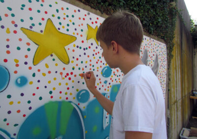Momentaufnahmen von der Graffiti-Aktion der Dörlinbacher Jugend bei der Alten Schule. 15 Jugendliche eine triste Stützmauer in ein leuchtendes Wandbild.
