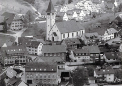 Blick vom Oberrain ins Dorf in den 1990er-Jahren. Im Dorfkern gut eingefangen „Löwen“, alte Fabrik, Rathaus, Post-Laden, Metzgerei und Kirche.